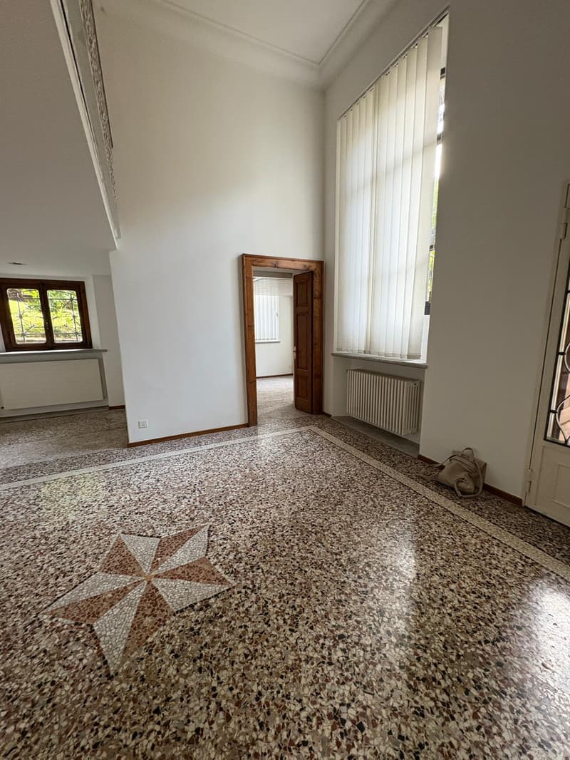 Empty room, white walls, star pattern floor, large windows, radiator, open door.
