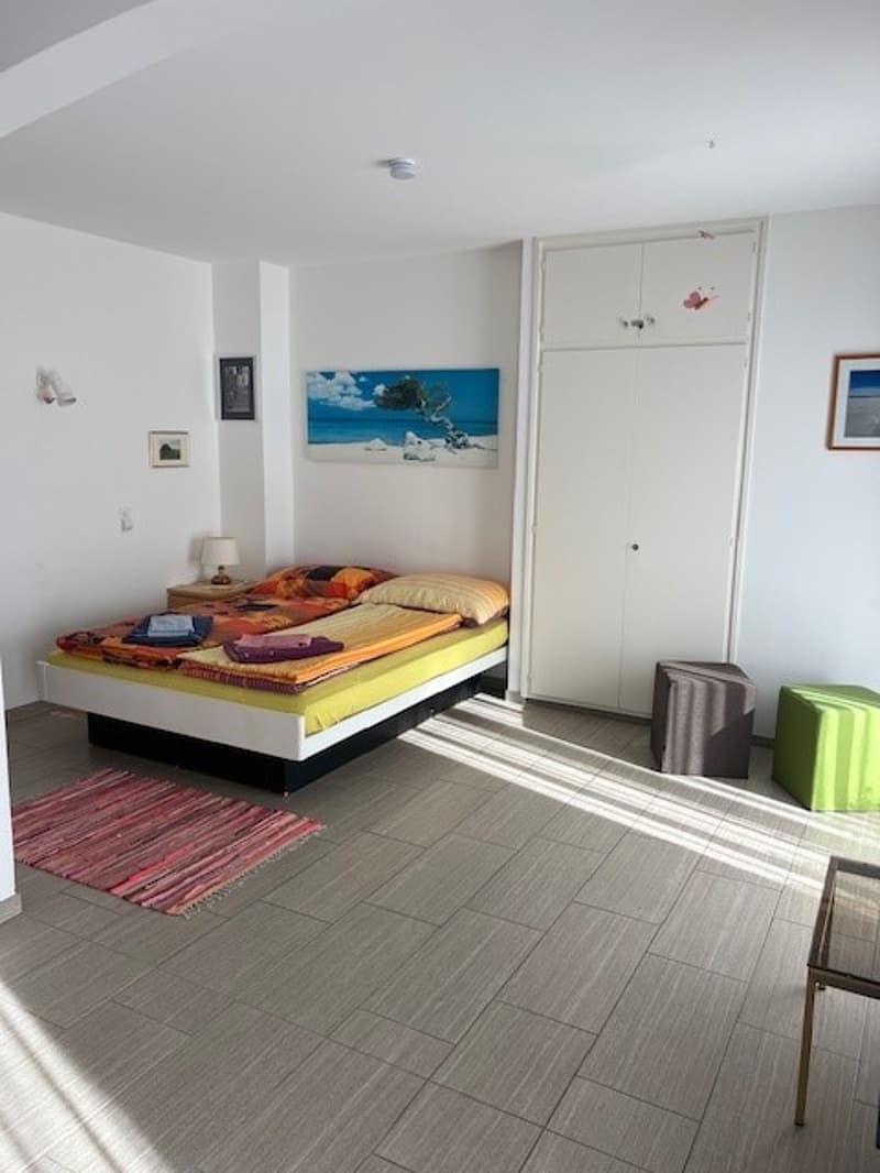 double bed, nightstand, lamp, rug, white wardrobe, picture frames, ottomans
