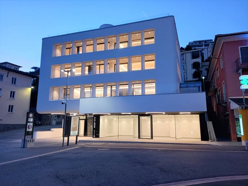 A modern, multi-story commercial building with a blue exterior and large windows. The building appears to have several floors and is located in an urban setting with other buildings nearby.