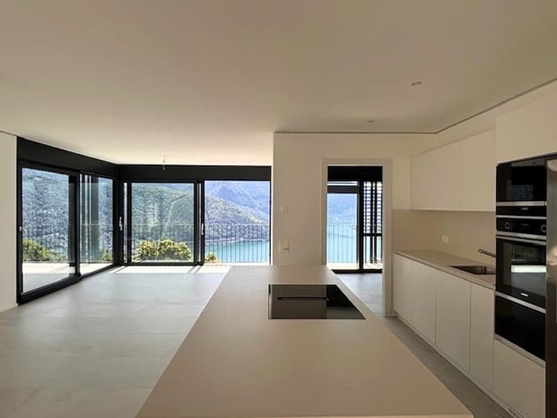 Spacious open-plan living area with large windows offering a scenic view, modern kitchen with built-in appliances, and access to a balcony or terrace.