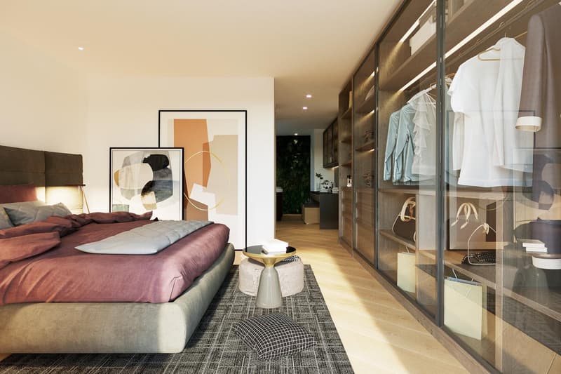 Spacious bedroom with a large bed, abstract artwork on the walls, and a glass-enclosed wardrobe area. The room has a warm, modern aesthetic with wooden floors and neutral tones.