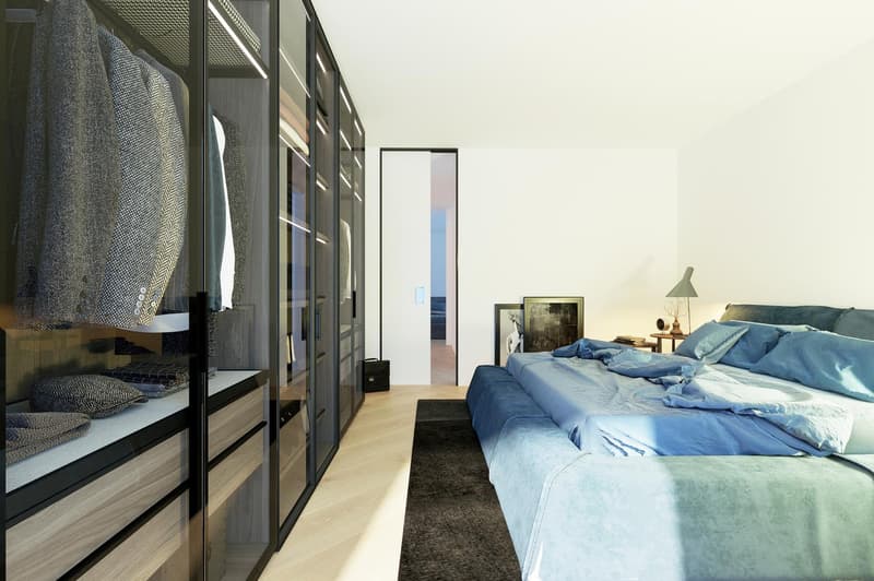 Spacious bedroom with large windows, walk-in closet, blue bedding, and a cozy seating area