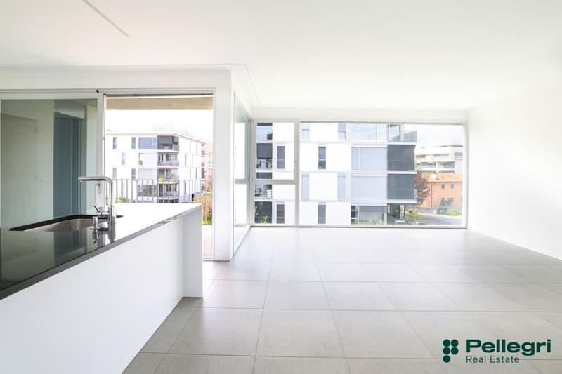 modern kitchen with large windows, balcony, stainless steel sink, black countertop, white cabinets