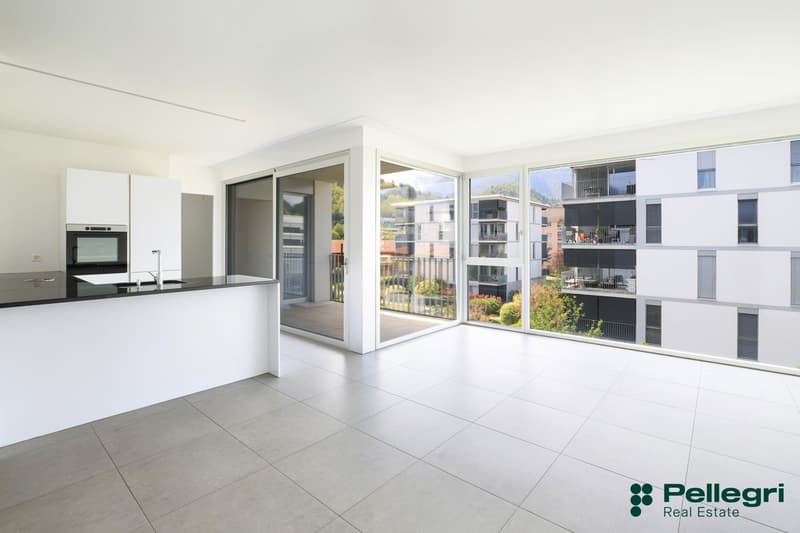 modern kitchen with white cabinets, black countertops, large windows, balcony
