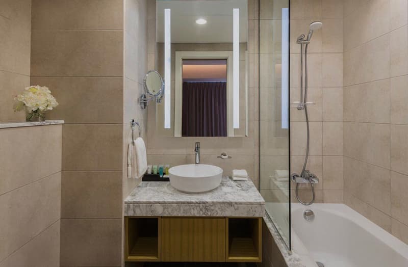 Bathroom with marble countertop, white sink, shower with glass door, bathtub, vanity mirror, faucet, toilet, wall-mounted towel rack
