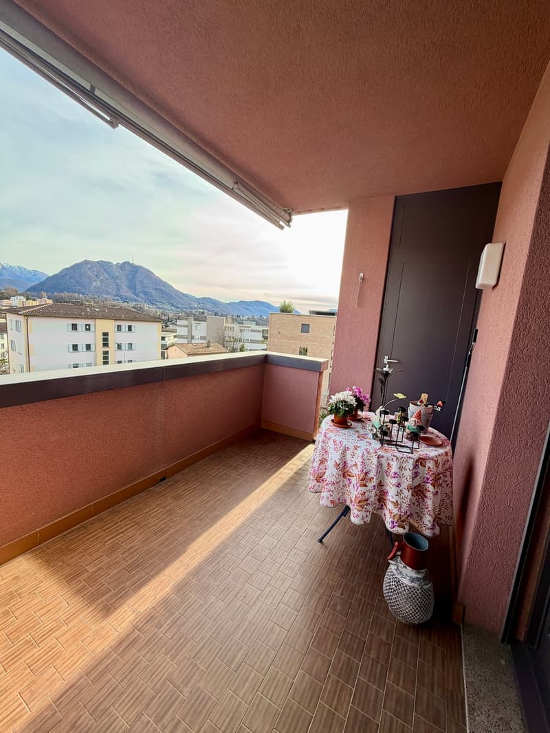 Balcony with wooden floor, table with flowers, vase, mountains view