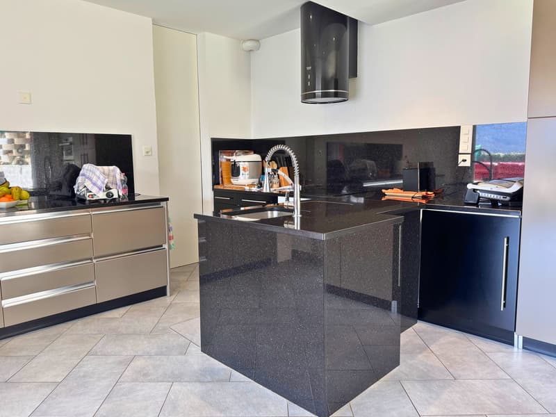 Modern kitchen with black granite countertops, built-in appliances including a dishwasher, and tile flooring.