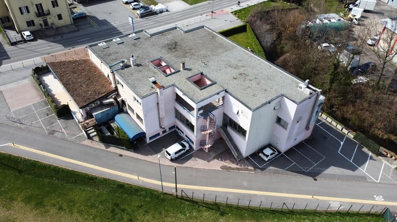 Three story building, concrete exterior, 2 parking places in front, spiral staircase on the back