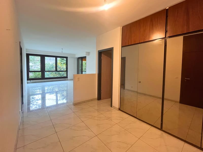 Empty room, white tiles, large windows, wooden wardrobes with mirror