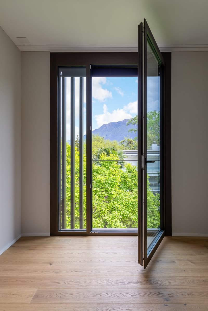 empty room, wooden floor, large glass door, view of trees and mountains