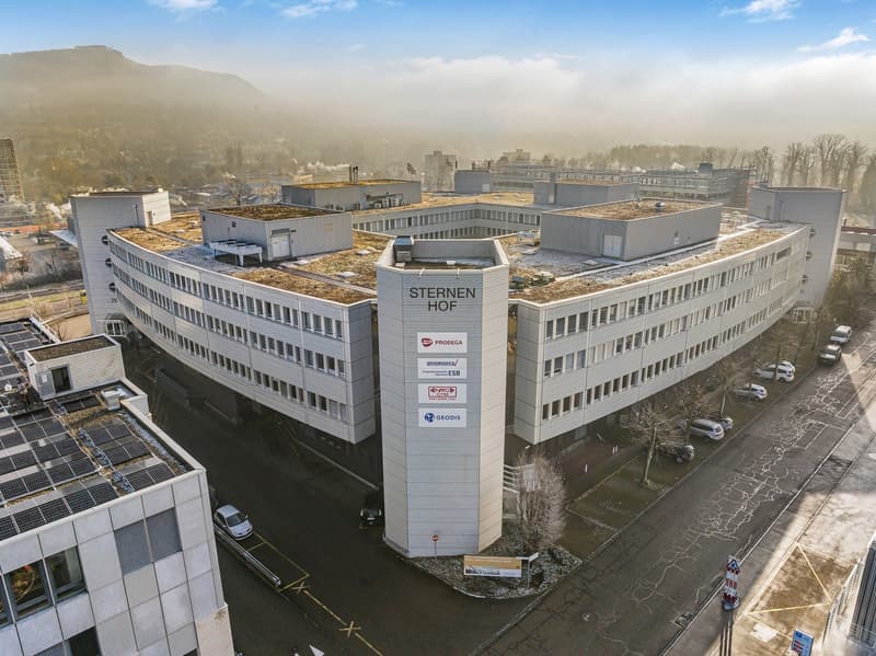 The image shows a large multi-story office building complex called Sternen Hof, with several interconnected buildings and a central tower structure. The buildings have flat roofs with greenery on top, likely serving as green roofs. The complex appears to