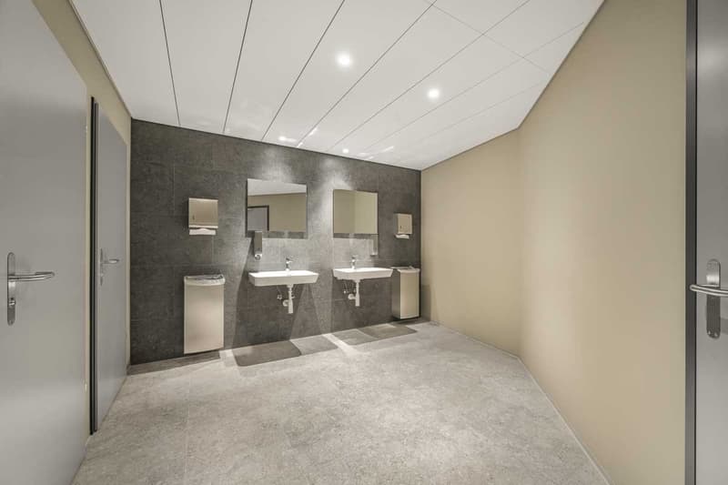 Large bathroom with double vanity sinks, mirrors, and tiled walls and floor