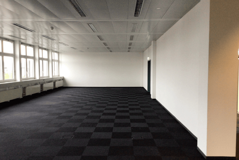 empty room, white walls, black and white floor, ceiling lights, windows with white frames