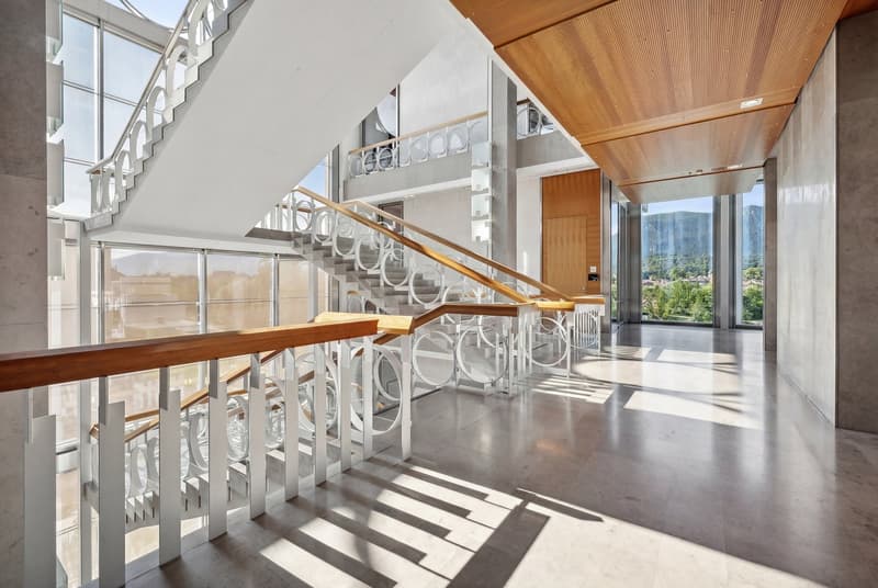 High ceiling, modern design staircase, glass walls, concrete flooring