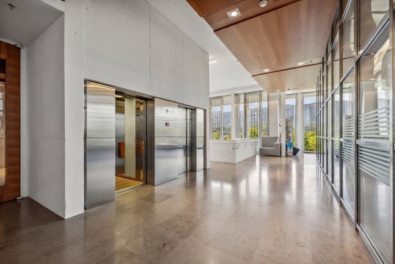 large hallway, two elevators, glass walls, shiny floors, bright