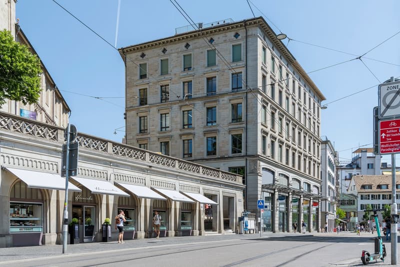 High building with many windows, stores with awnings, tramline wires