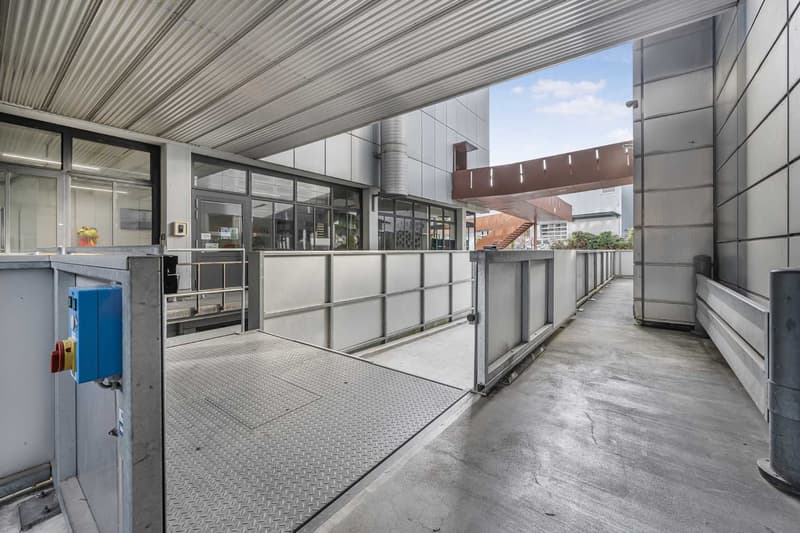Concrete ramp leading to elevated entrance with glass doors