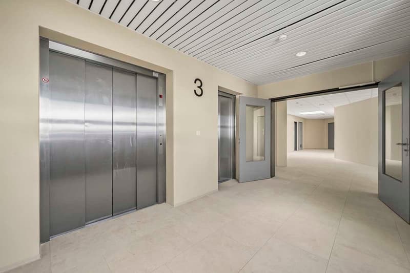modern building interior, steel elevator doors, beige tiles, white walls, light ceiling, open entrance doors, empty hallway