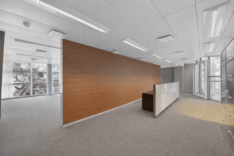 empty office space with wooden partition, reception desk, grey carpet, white ceiling, large windows