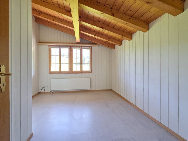 Empty room, wooden beams, white walls, wooden floor, window, white radiator