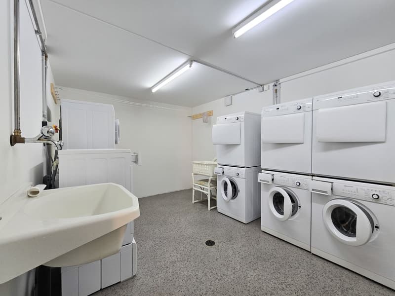 Laundry room with washing machines, dryers, and a sink.