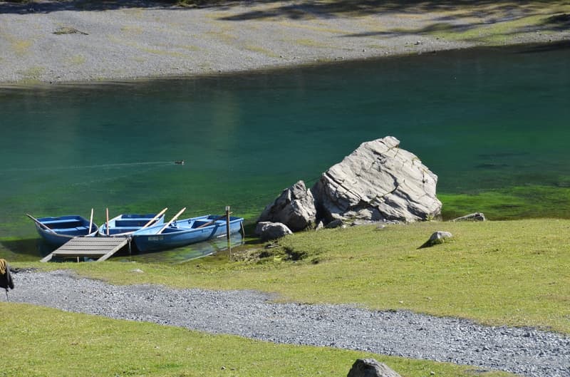 lake with boats, rocks, grassy area, wooden dock