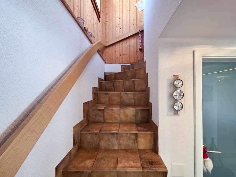 wooden staircase with brown tiles, wooden handrail, white walls