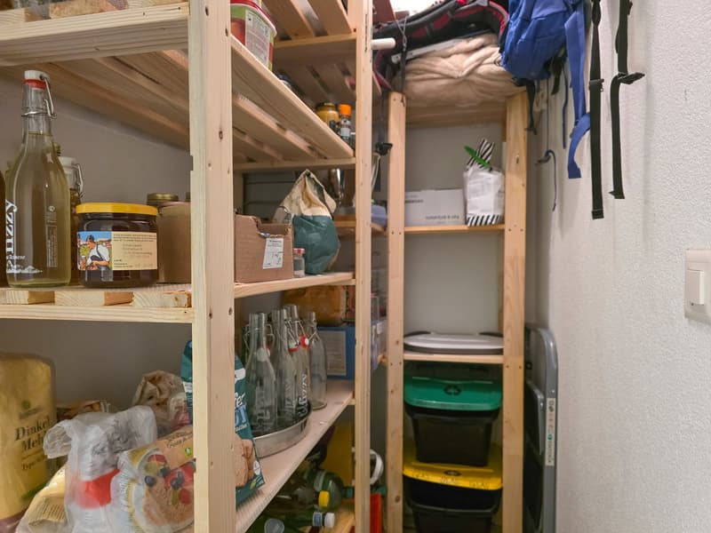 Wooden shelves, various food items, bottles, storage boxes, bags, and a backpack