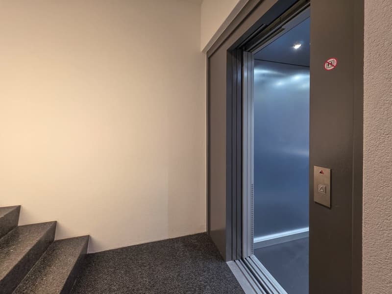 elevator door, carpeted floor, white wall, gray door, light inside elevator