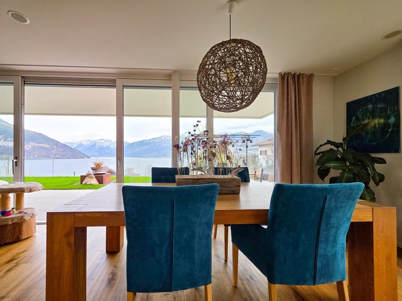 dining room with wooden table, blue chairs, large windows, wooden floor, decorative items, plants, lake view