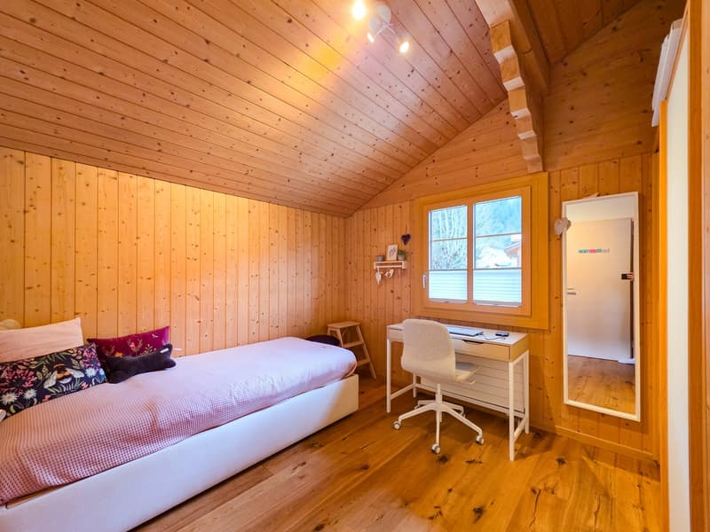 Single bed, desk, chair, wooden walls, window, mirror, wooden floor