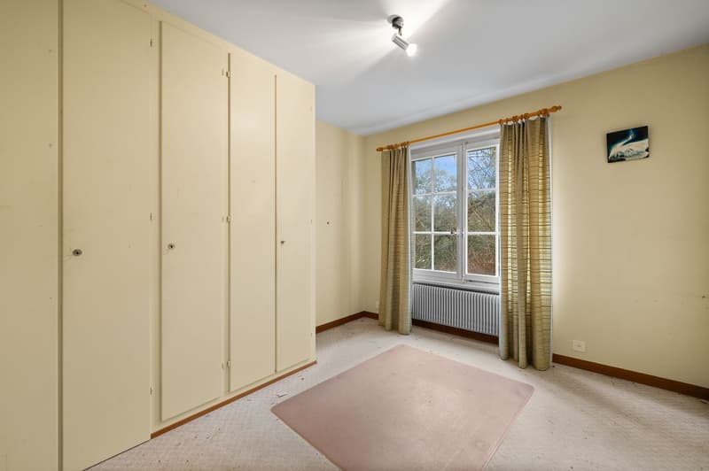 Empty room with yellow walls, beige flooring, a large closet, a window with curtains, and a radiator beneath.