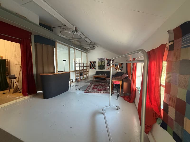 spacious room, white floor, large windows, red curtains, table, chairs, shelves, floor lamp, rug, clothing racks, curtains on rod