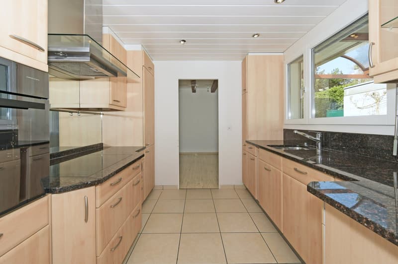 modern kitchen with wooden cabinets, granite countertops, stainless steel appliances, and a large window