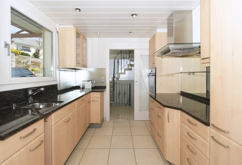 modern kitchen with wooden cabinets, granite countertops, stainless steel appliances, spiral staircase