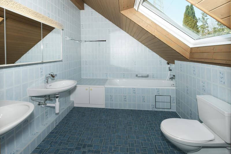 Bathroom with blue tiles, white fixtures, bathtub, sink, toilet, mirror, skylight