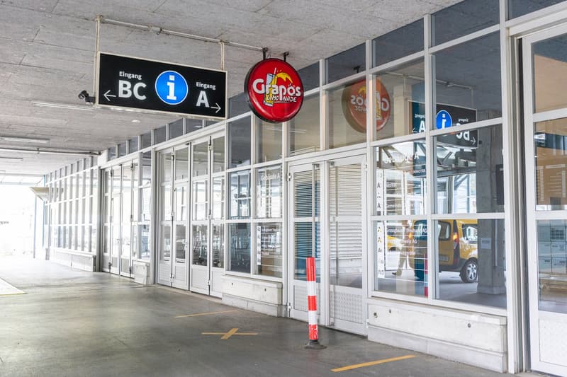 The image shows the exterior of a commercial building with glass doors and windows. There are signs indicating the entrance and exit (BC A and BC) as well as a large Granado's logo. The building appears to have a parking area in front of it.