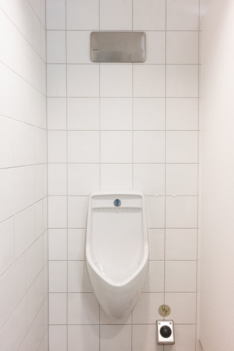White tiled walls, white toilet, and a washing machine visible in the image.
