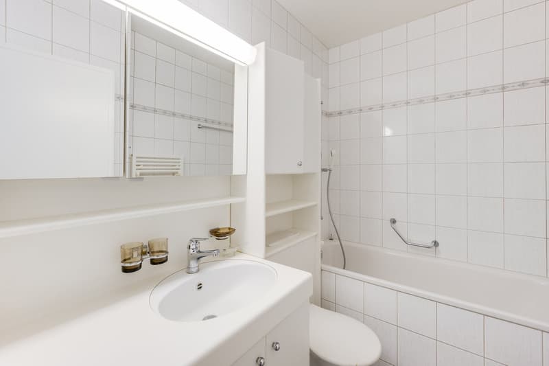 white tiles, white sink, white toilet, white bathtub, white mirror, white cabinet