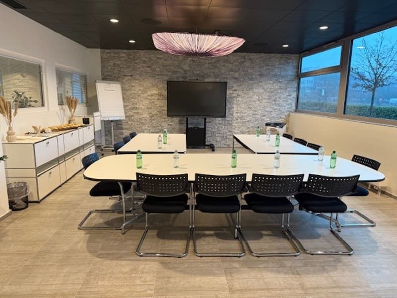 conference room with long tables, chairs, television, whiteboard, cabinets, trash bin