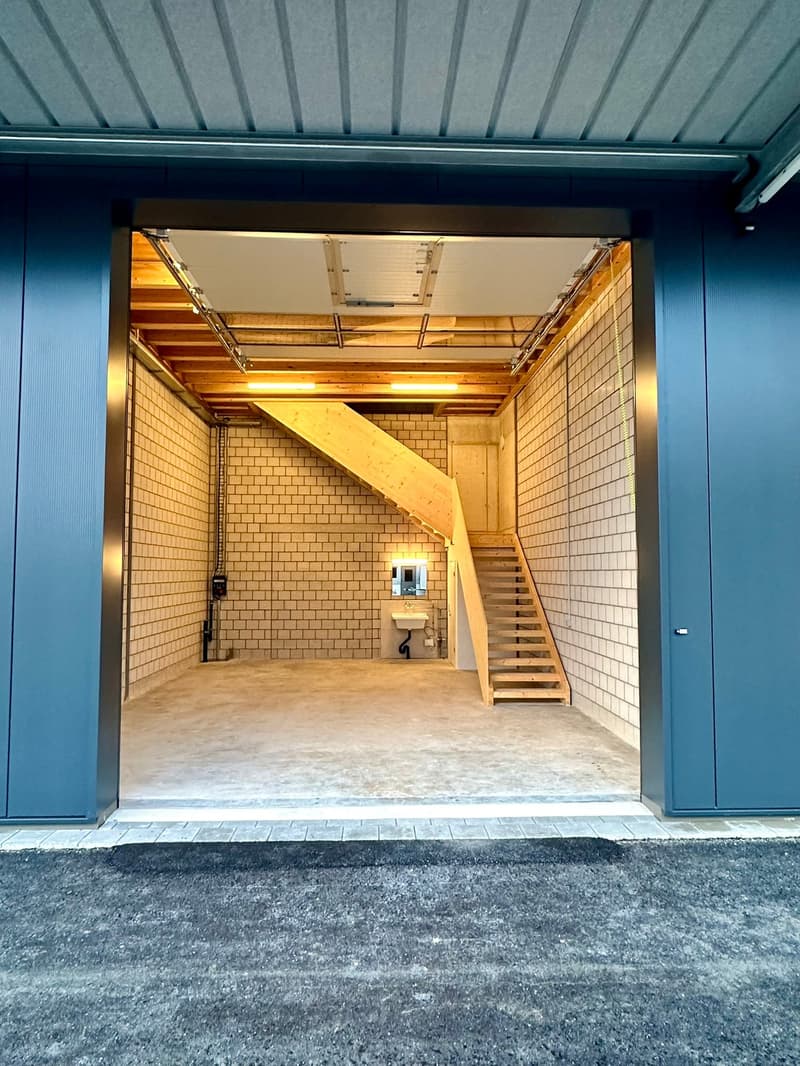 blue exterior doors, wooden staircase, white brick walls, concrete floor, open garage door