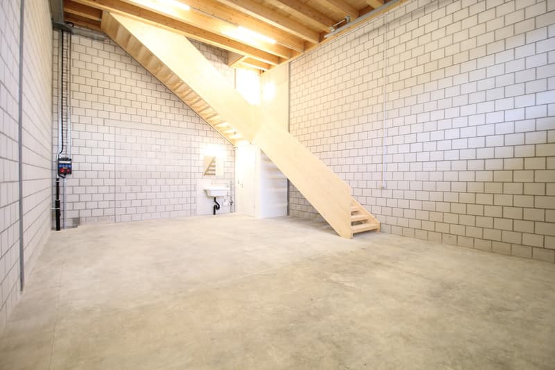 cement floor, white brick walls, wooden staircase, sink