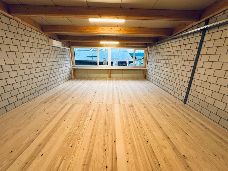Empty room, wooden floors, white brick walls, large window with solar panels view.