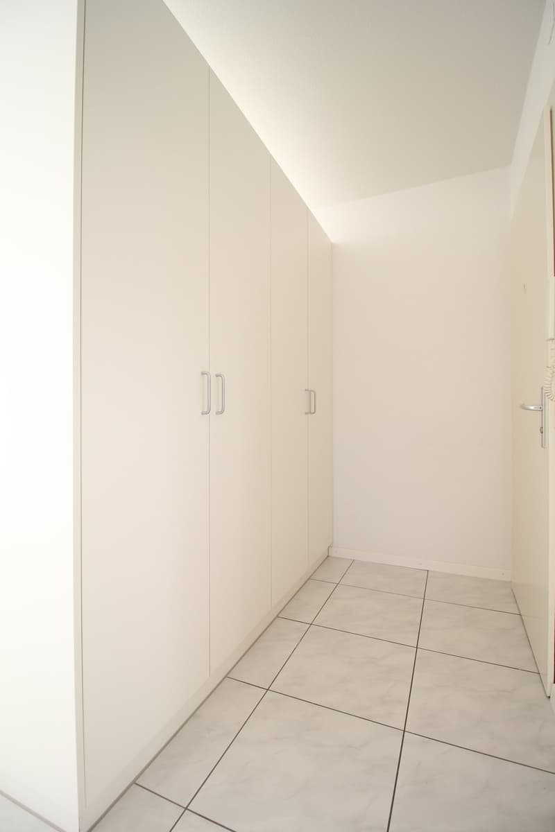 Empty room with white walls, white floor, and built-in wardrobes