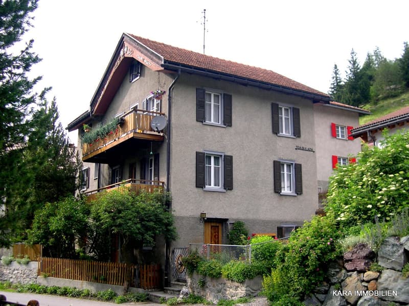 multilevel house, three floors, brown roof, brown shutters, multiple balconies, red shutters, trees, rock wall, entrance on ground floor