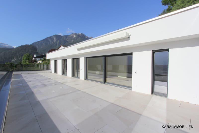 White modern house with balcony and terrace, large windows, tiled floor, view of mountains