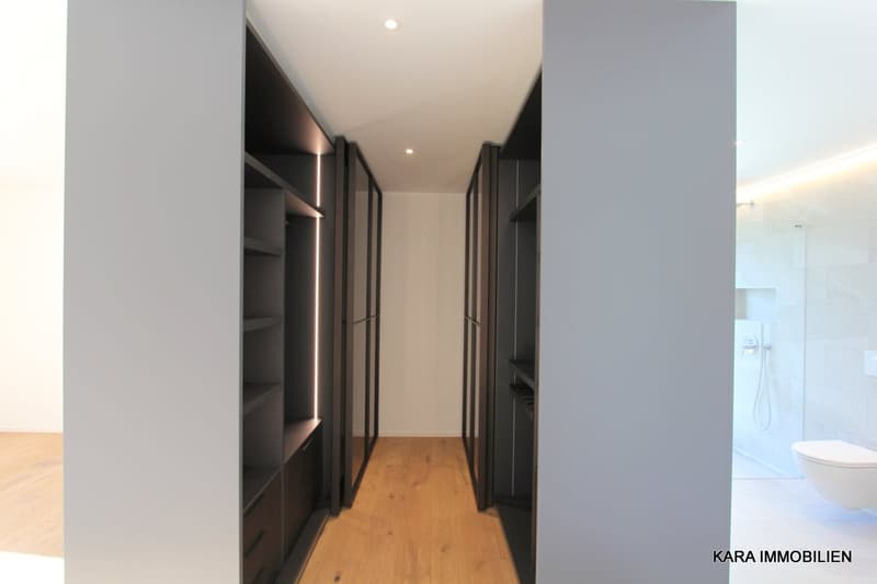 Walk-in closet with built-in drawers and shelves, modern white tiles, open wooden floor