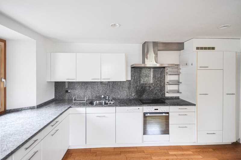 Modern kitchen with white cabinets, granite countertops, stainless steel appliances including a dishwasher, and hardwood flooring
