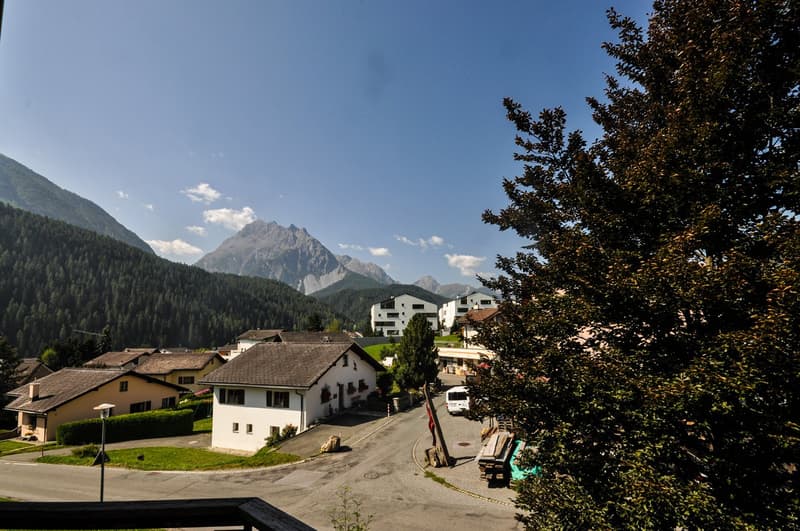 Aerial view of the village of Maloja in Switzerland. Mountainous area with several houses and clear blue skies.