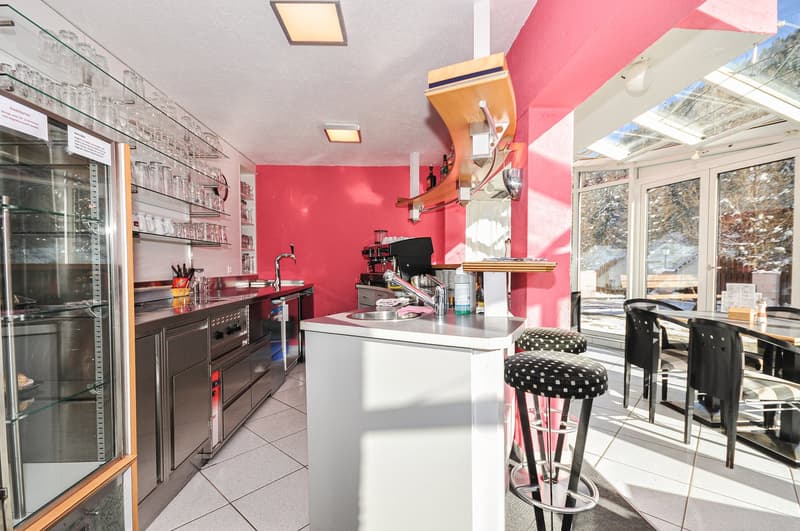 open kitchen, white tiles, stainless steel appliances, red wall, glass display case, glass shelves, tables and chairs